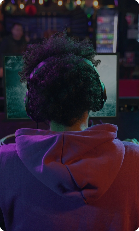 Een esports-speler zit achter een gamingcomputer met headset op en kijkt geconcentreerd naar het scherm tijdens een wedstrijd.
