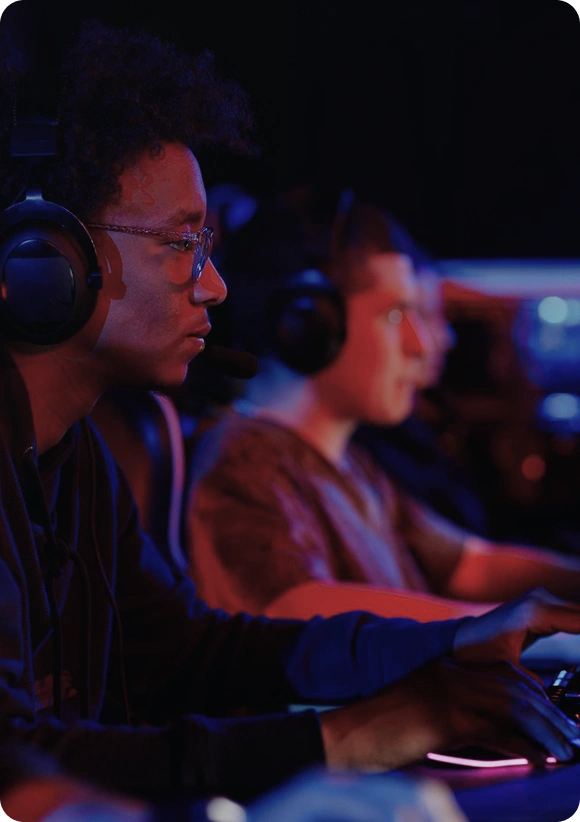 Twee esports-spelers zitten naast elkaar achter gamingcomputers en spelen geconcentreerd tijdens een toernooi, met focus op hun schermen.